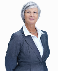 A woman with short grey hair wearing a navy suit, white collared shirt, and gold necklace.